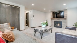 A living room with a sofa, a coffee table, a fireplace, and a TV mounted on the wall.