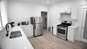A modern kitchen with stainless steel appliances, white cabinetry, and a light wood floor.