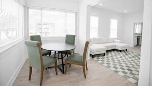 A modern living room with a round table and chairs, a white sofa, and a checkered rug.
