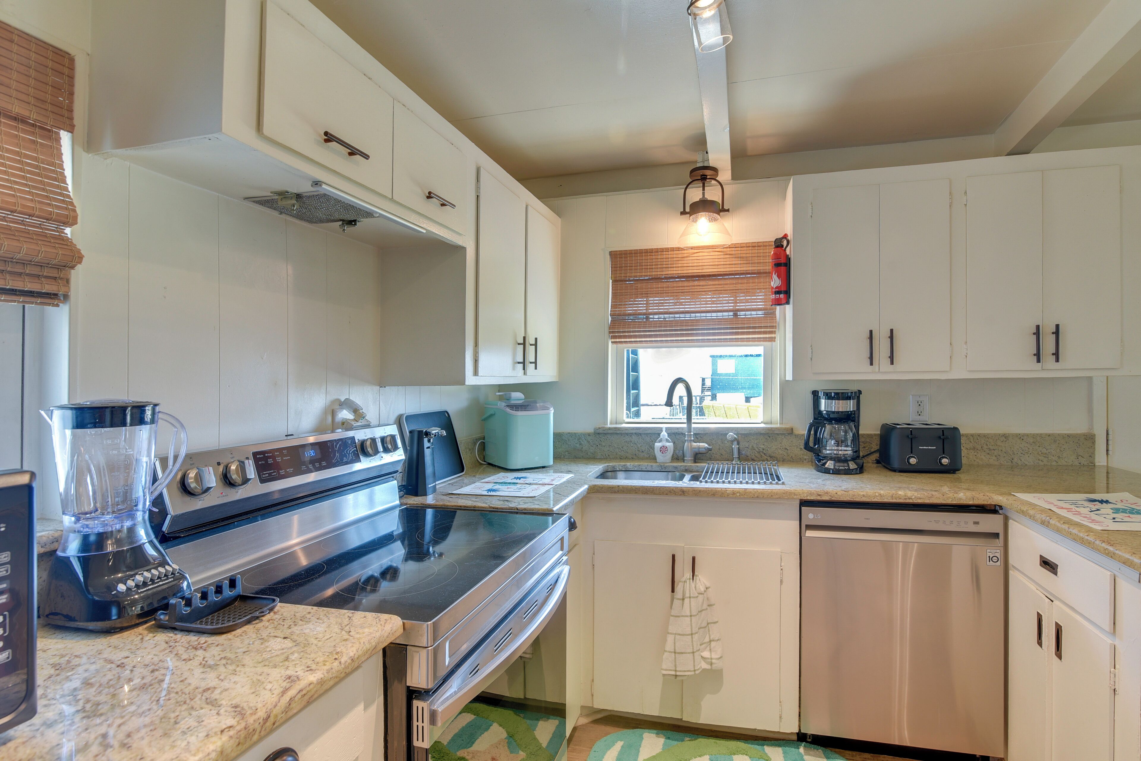 A kitchen with white cabinets, a stainless steel stove, a dishwasher, and a coffee maker.