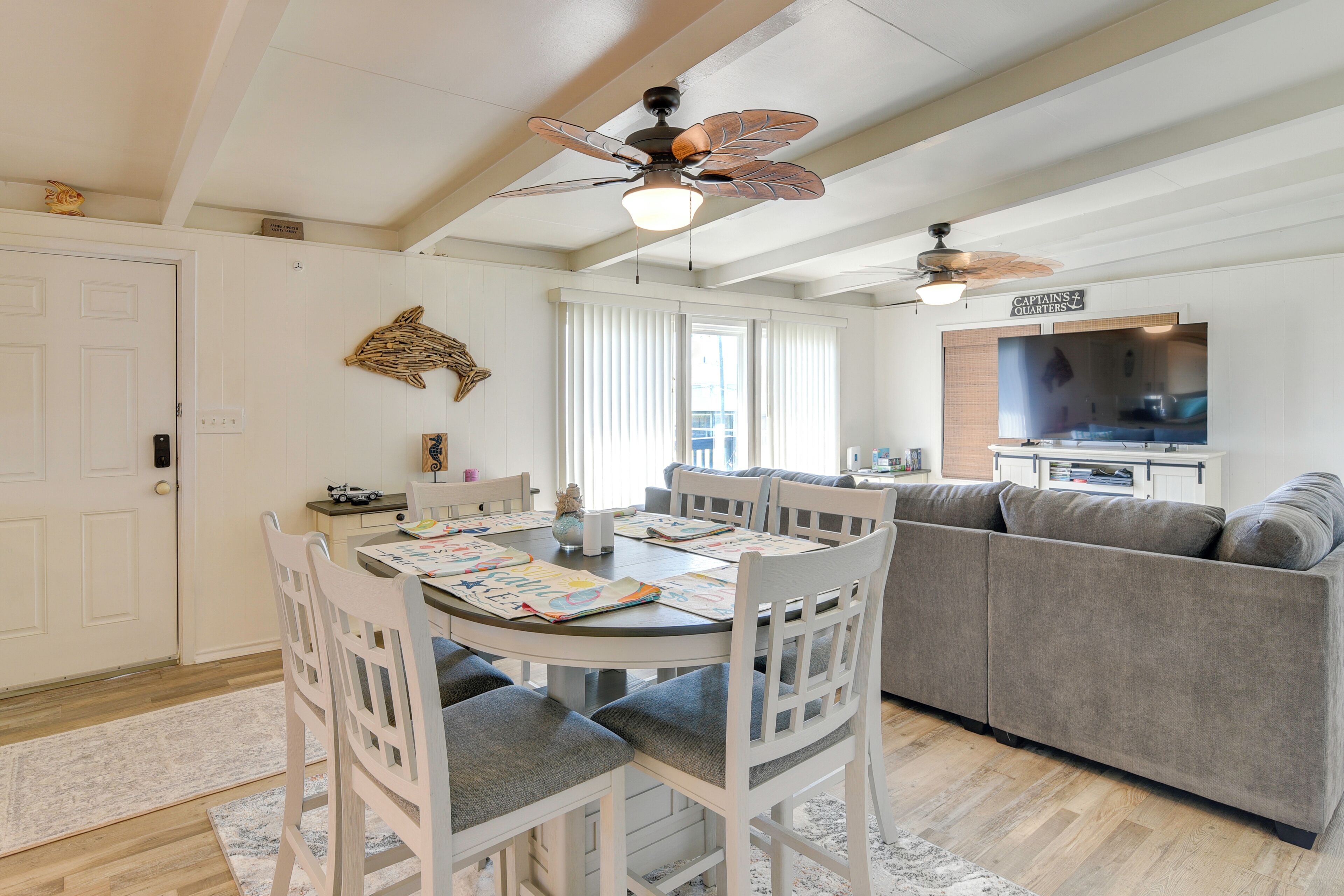 A dining area with a round table, white chairs, and a ceiling fan.