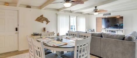 A dining area with a round table, white chairs, and a ceiling fan.