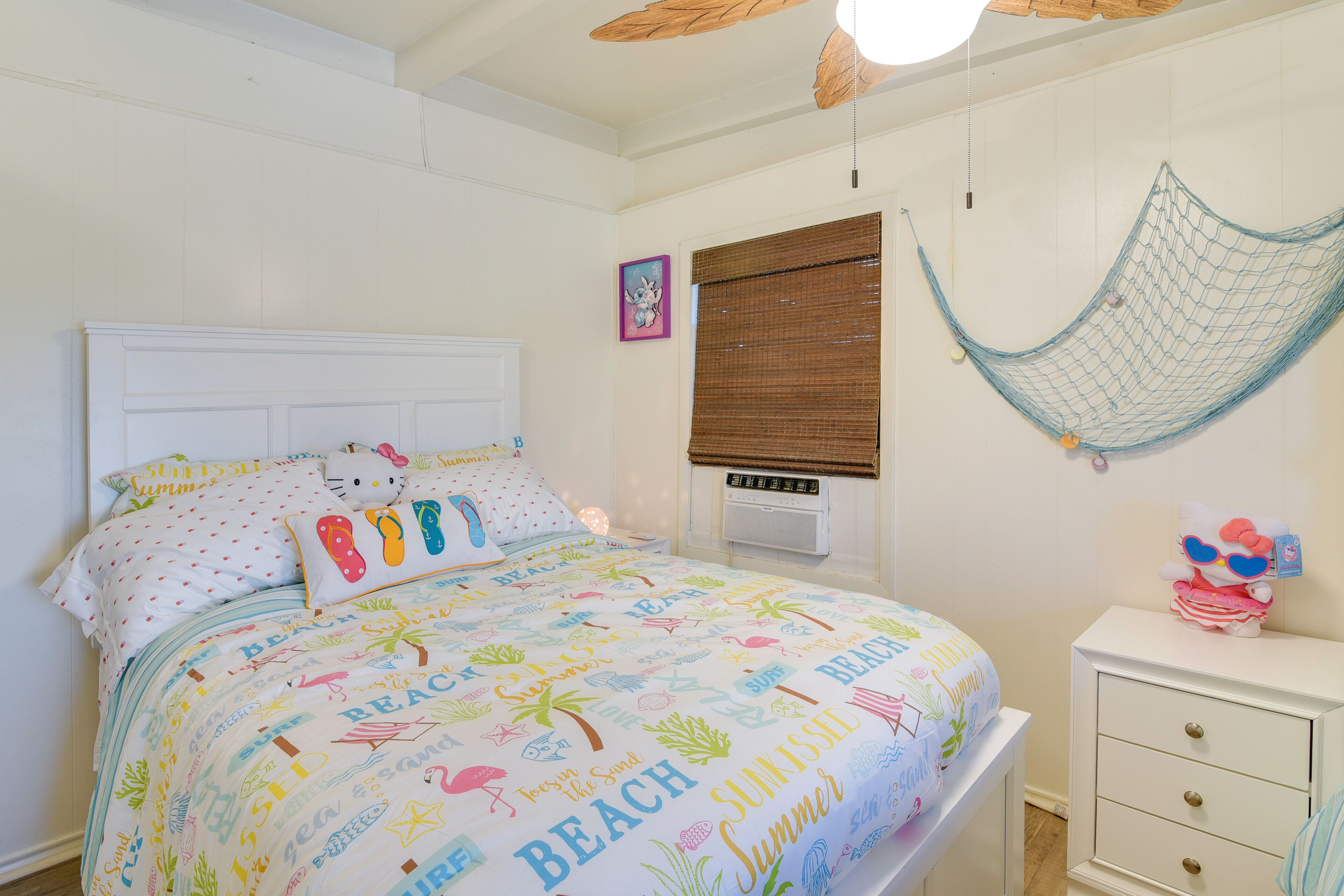 Une chambre à coucher comprenant un lit, une table de chevet, un hamac, une fenêtre avec des stores et un radiateur fixé au mur.