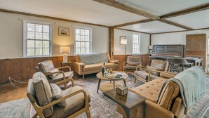 A spacious living room with wooden beams, multiple seating options, a fireplace, and large windows. - 4 Mi to Noannet Pond: Pet-friendly Home w/ Yard (Dover)