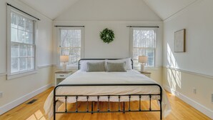 A bedroom with a bed, two bedside tables, a wall-mounted wreath, and large windows. - 4 Mi to Noannet Pond: Pet-friendly Home w/ Yard (Dover)