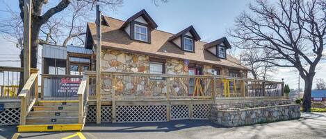 A two-story building with a stone facade, a wooden deck, and a staircase leading to the entrance.