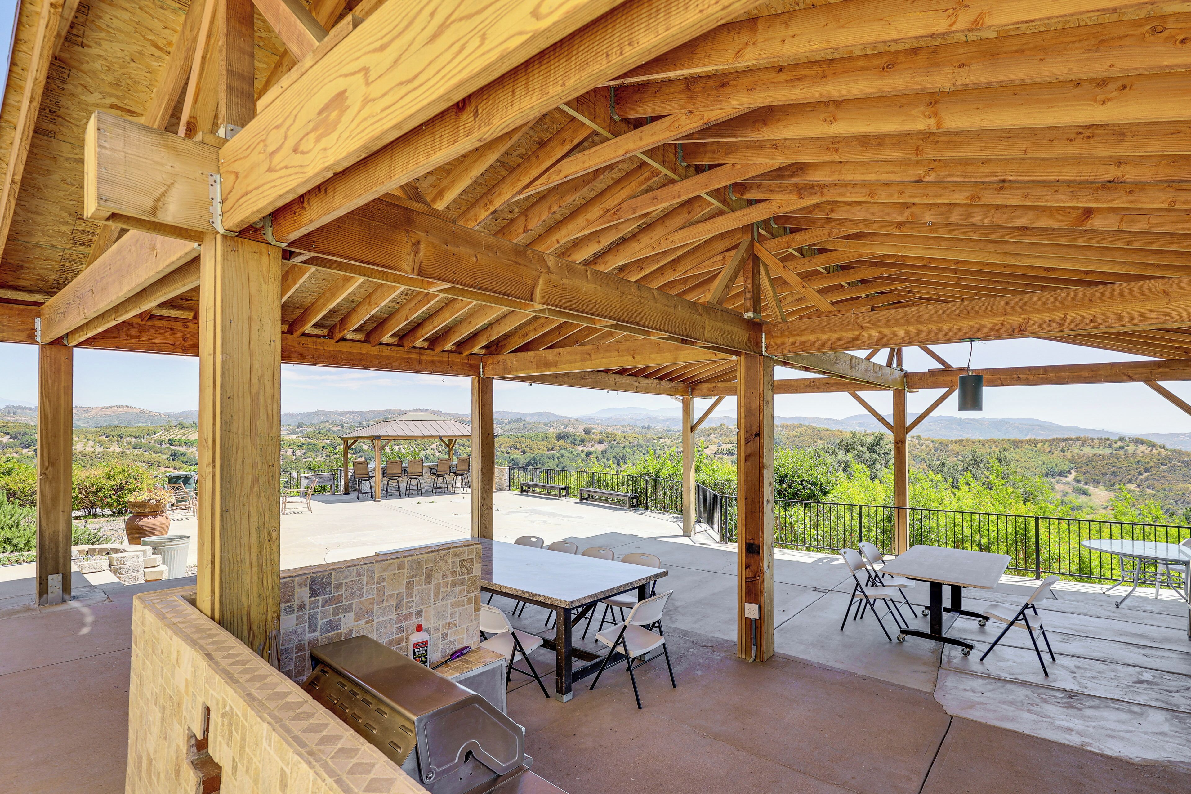 Un patio al aire libre con una pérgola de madera, una parrilla y una mesa con sillas.