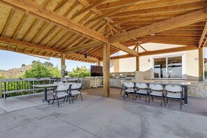 An outdoor patio with a wooden roof, concrete flooring, and white chairs. - Outdoor Oasis w/ Valley Views: Temecula Escape (Temecula)