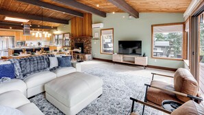 Una sala de estar moderna con un sofá modular, una chimenea, un televisor y una zona de cocina.
