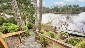 Una escalera de madera que conduce a una zona junto al lago con bancos y una pequeña estructura.