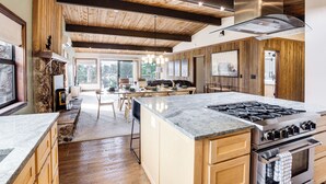 Una cocina amplia con una isla grande, armarios de madera y una pared de acento de piedra.