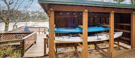 A wooden structure with kayaks and a covered seating area.