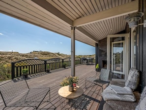 A covered outdoor area with a wooden deck, seating, and a view of the landscape. - 4 Star Holiday Home in Saltum (Saltum)