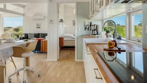 A modern kitchen with a large window, wooden cabinets, and a dining area with a table and chairs. - 4 Star Holiday Home in Saltum (Saltum)