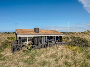 A modern house with a grass roof, a covered porch, and a view of the surrounding landscape. - 4 Star Holiday Home in Saltum (Saltum)