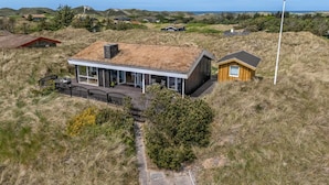 A modern house with a large glass facade, a wooden structure, and a flagpole. - 4 Star Holiday Home in Saltum (Saltum)