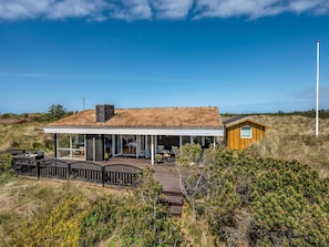 A modern house with a thatched roof, large windows, and a wooden exterior. - 4 Star Holiday Home in Saltum (Saltum)