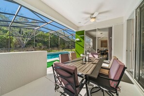An outdoor patio with a pool, a table with chairs, and a glass door leading to an interior space. - Sleeps 12 • Pvt pool & spa • Game table (Kissimmee)