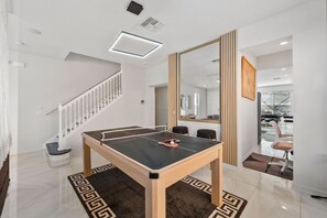 A ping pong table in a modern room with a staircase and a large mirror. - Sleeps 12 • Pvt pool & spa • Game table (Kissimmee)