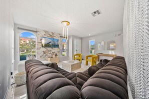 A modern living room with a sofa, chairs, a coffee table, and a painting on the wall. - Sleeps 12 • Pvt pool & spa • Game table (Kissimmee)
