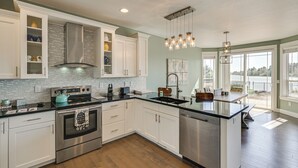 A modern kitchen with stainless steel appliances, white cabinetry, and a large island. - Lakefront Getaway w/ Private Dock in Ocean Shores! (Ocean Shores)