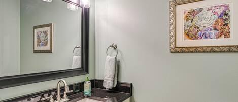 A bathroom with a sink, mirror, towel rack, and framed artwork on the wall.