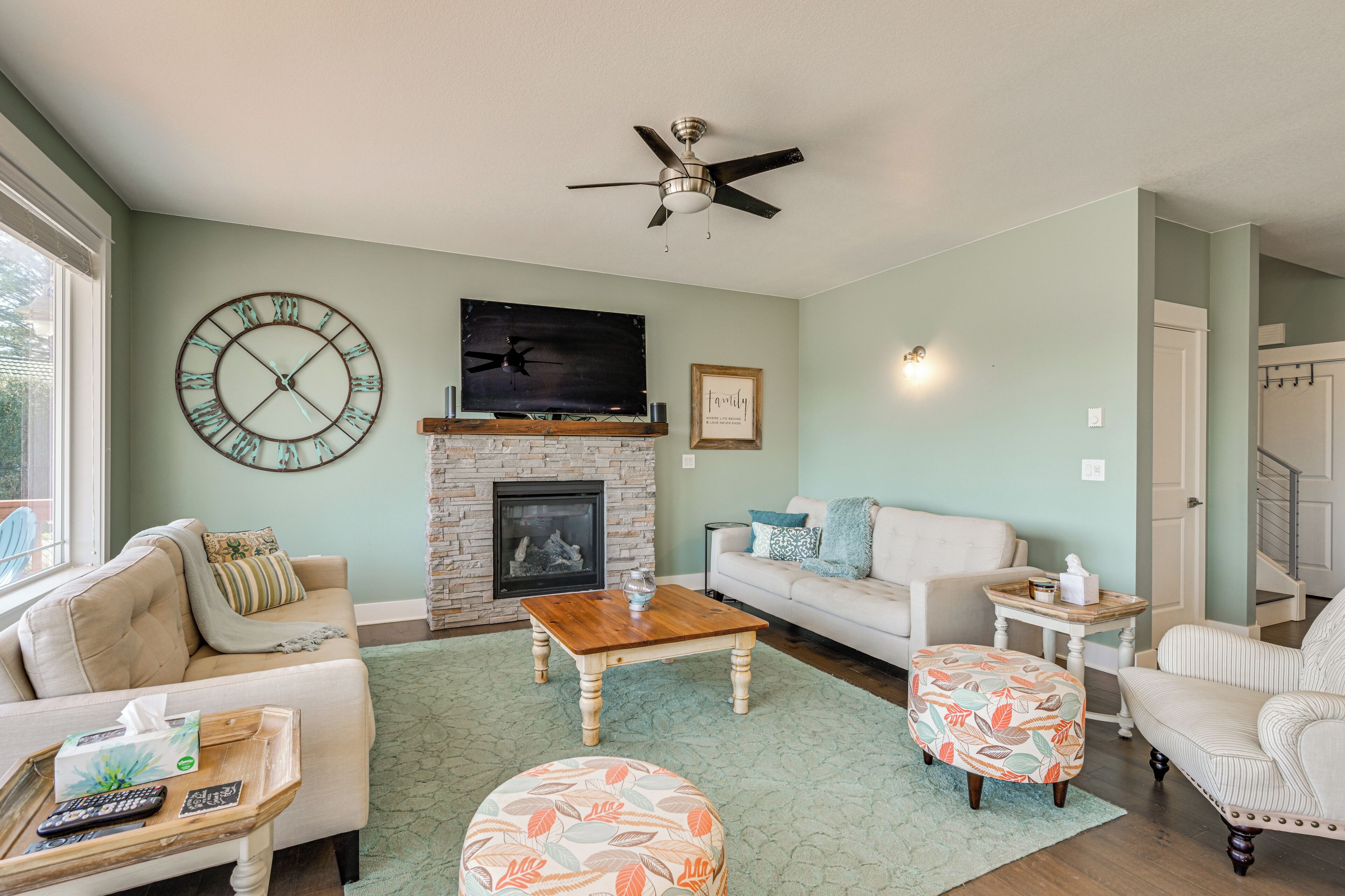 A living room with a fireplace, a clock, a ceiling fan, and a sofa.