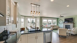 A spacious kitchen with a large island, a dining area with a fireplace, and a living room with a sofa and a TV. - Lakefront Getaway w/ Private Dock in Ocean Shores! (Ocean Shores)