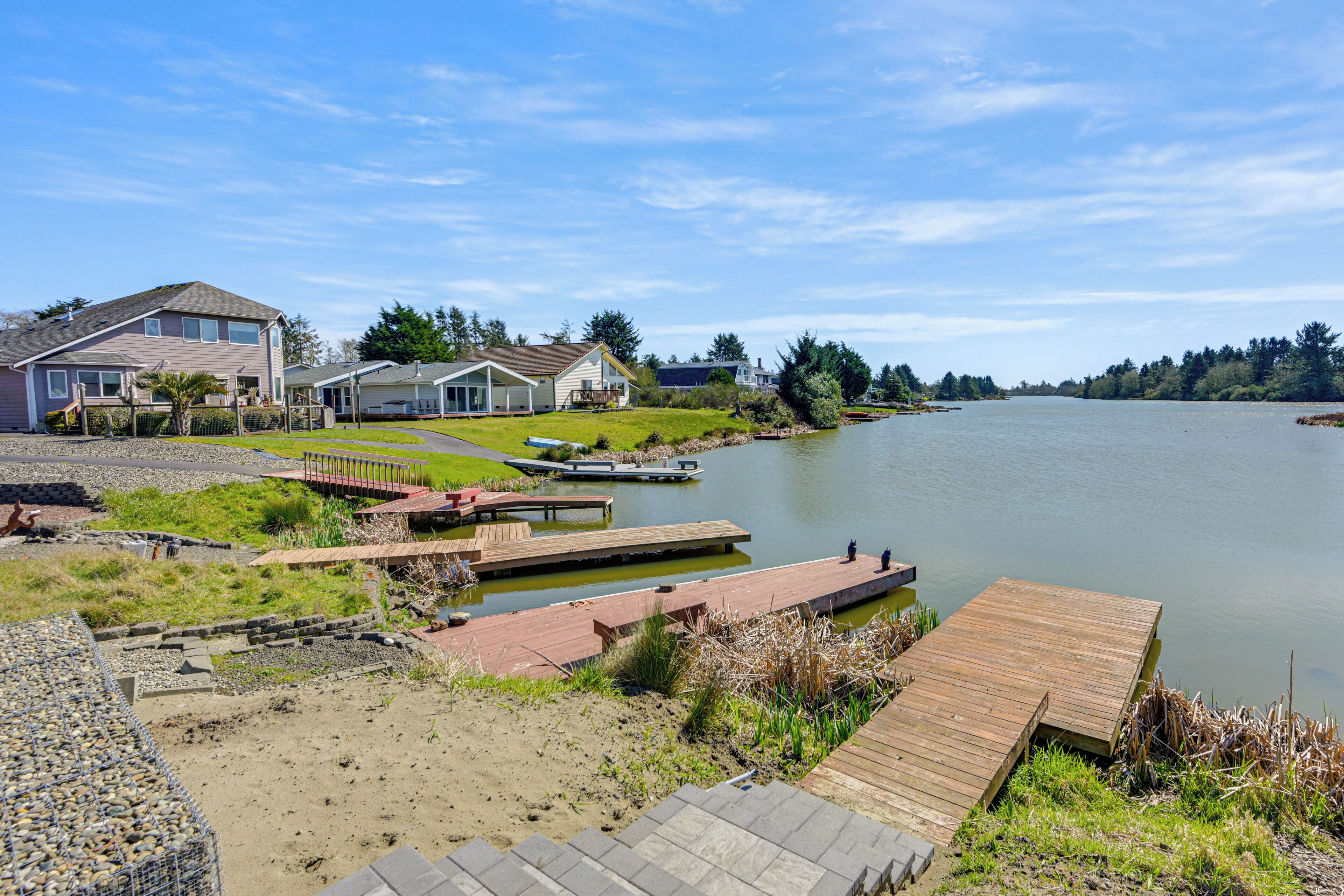 A lakeside property with a dock, a grassy area, and houses in the background.