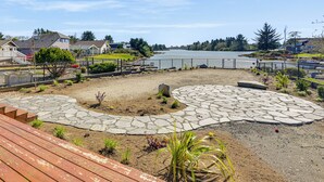 A lakeside deck with stone pathways, a wooden deck in the foreground, and houses in the background. - Lakefront Getaway w/ Private Dock in Ocean Shores! (Ocean Shores)