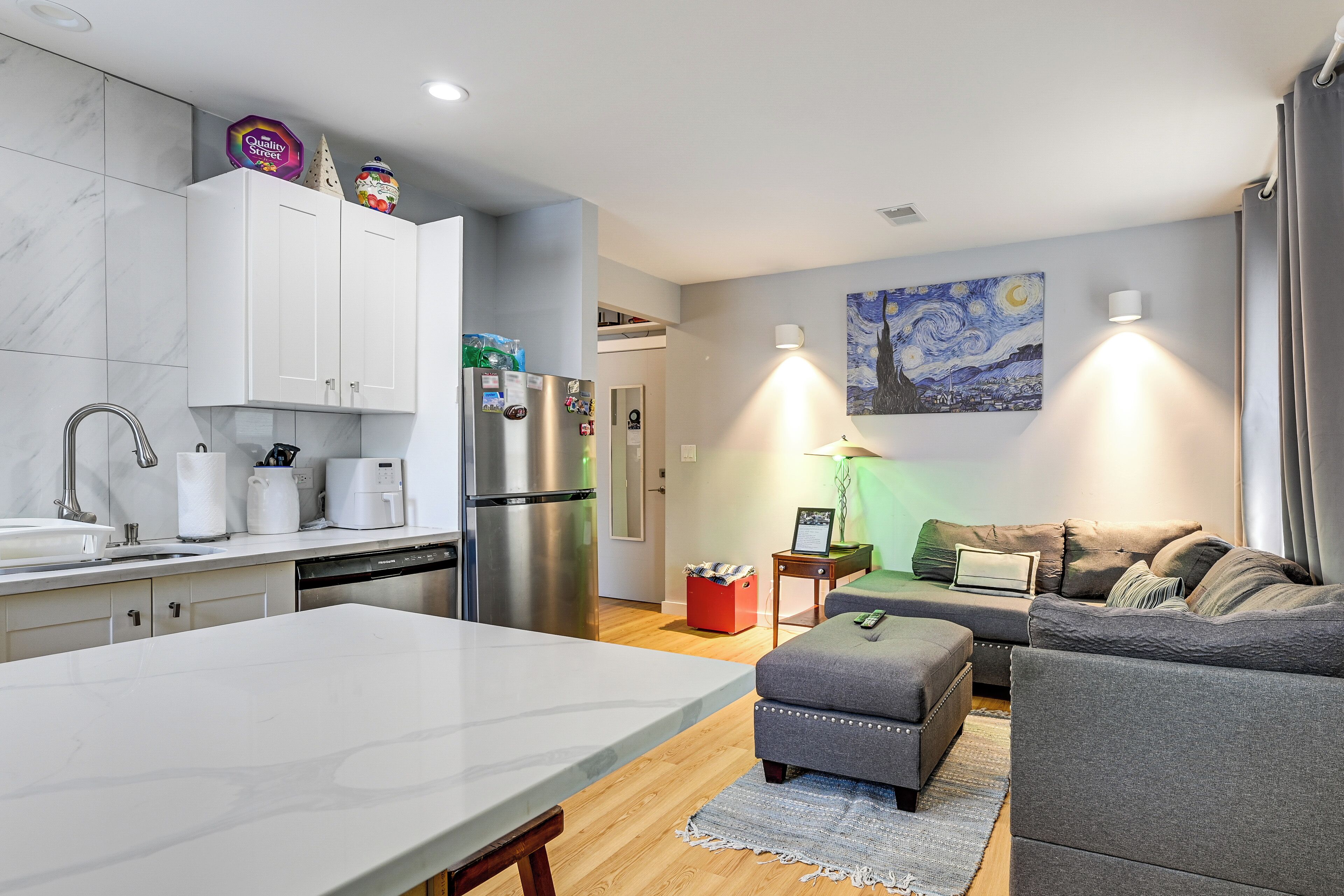 A modern kitchen with white cabinets, a stainless steel refrigerator, and a dining area with a marble table.