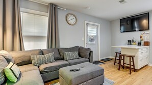 Ein Wohnzimmer mit einer Couch, einem Hocker und einem Fernseher.