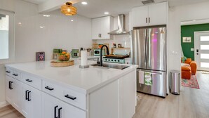 A modern kitchen with white cabinetry, a stainless steel refrigerator, and a central island. - Yard Games, Outdoor Kitchen: Palm Springs Retreat! (Palm Springs)