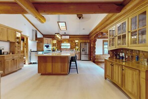 A spacious kitchen with wooden cabinets, a central island, and a large refrigerator. - Hot Tub + Dock! Waterfront Norris Lake Log Home (New Tazewell)