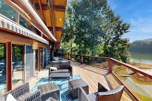 Eine Holzterrasse mit Korbmöbeln und einer Glastür, die zu einem Raum führt.
