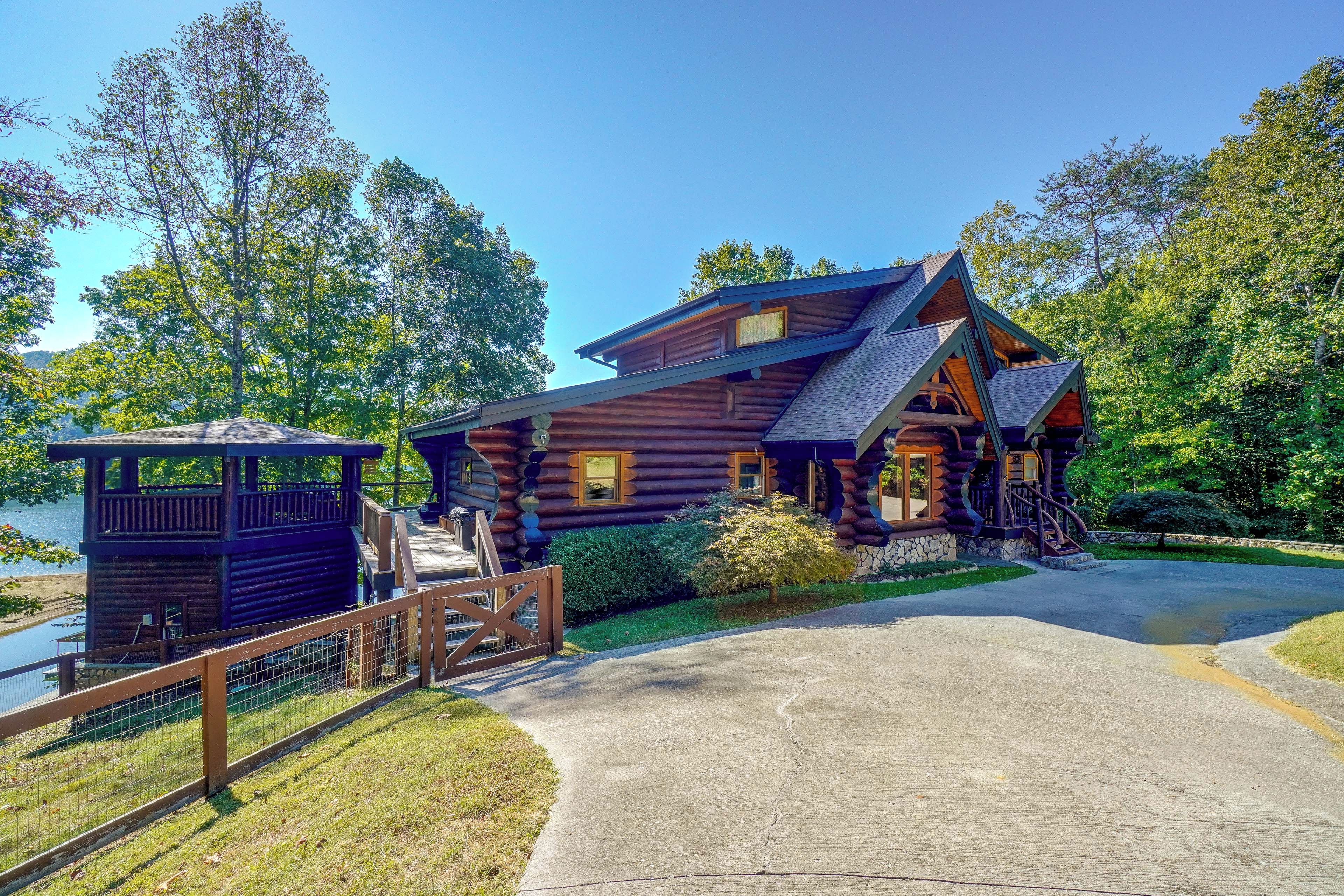 A log cabin with a porch, a small tower, and a stone wall.