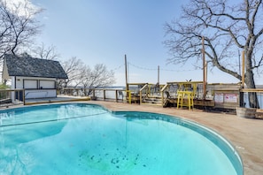 Piscina com deck de madeira, posto de salva-vidas e vista da região ao redor.