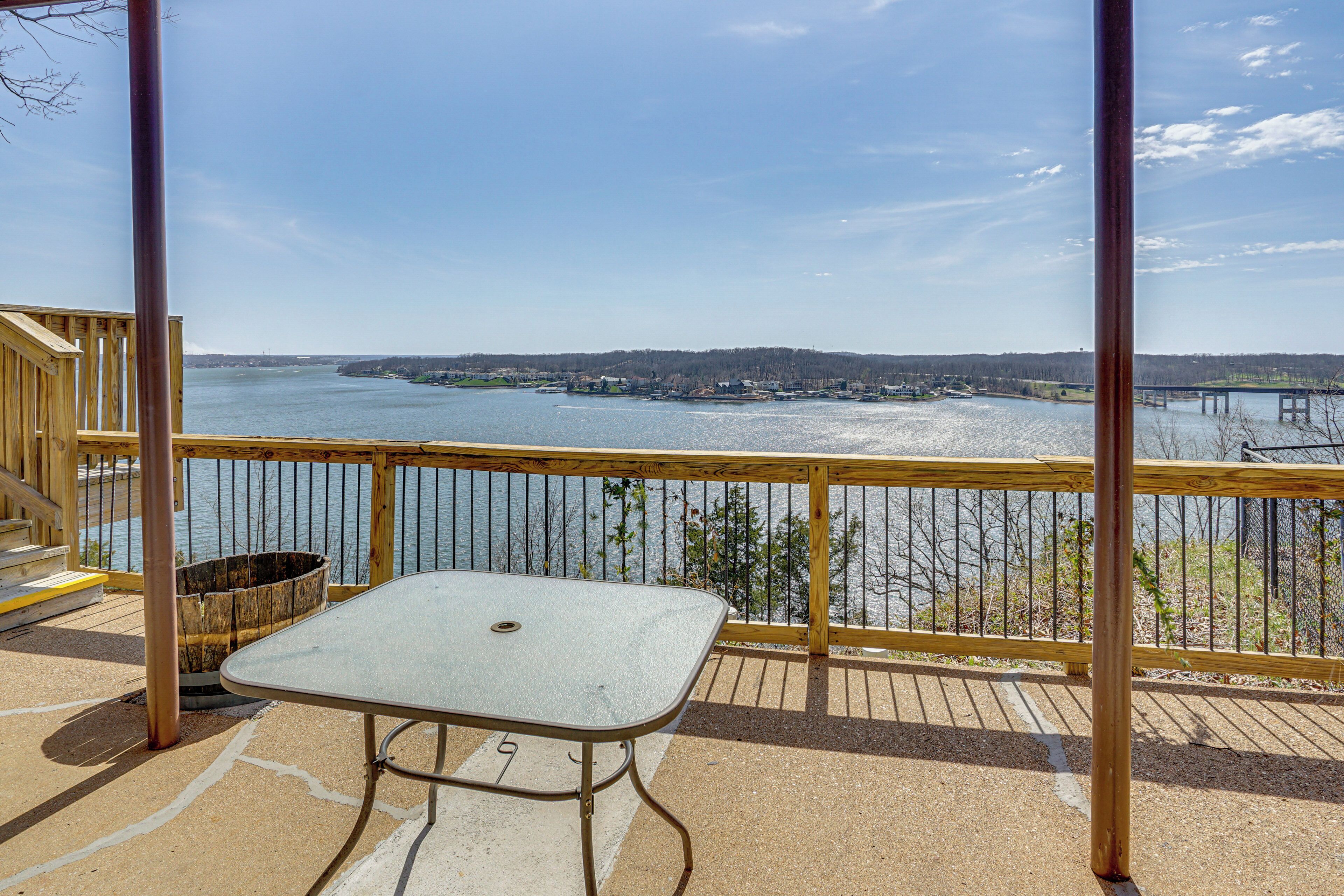 A balcony with a table and a view of a body of water and distant land.