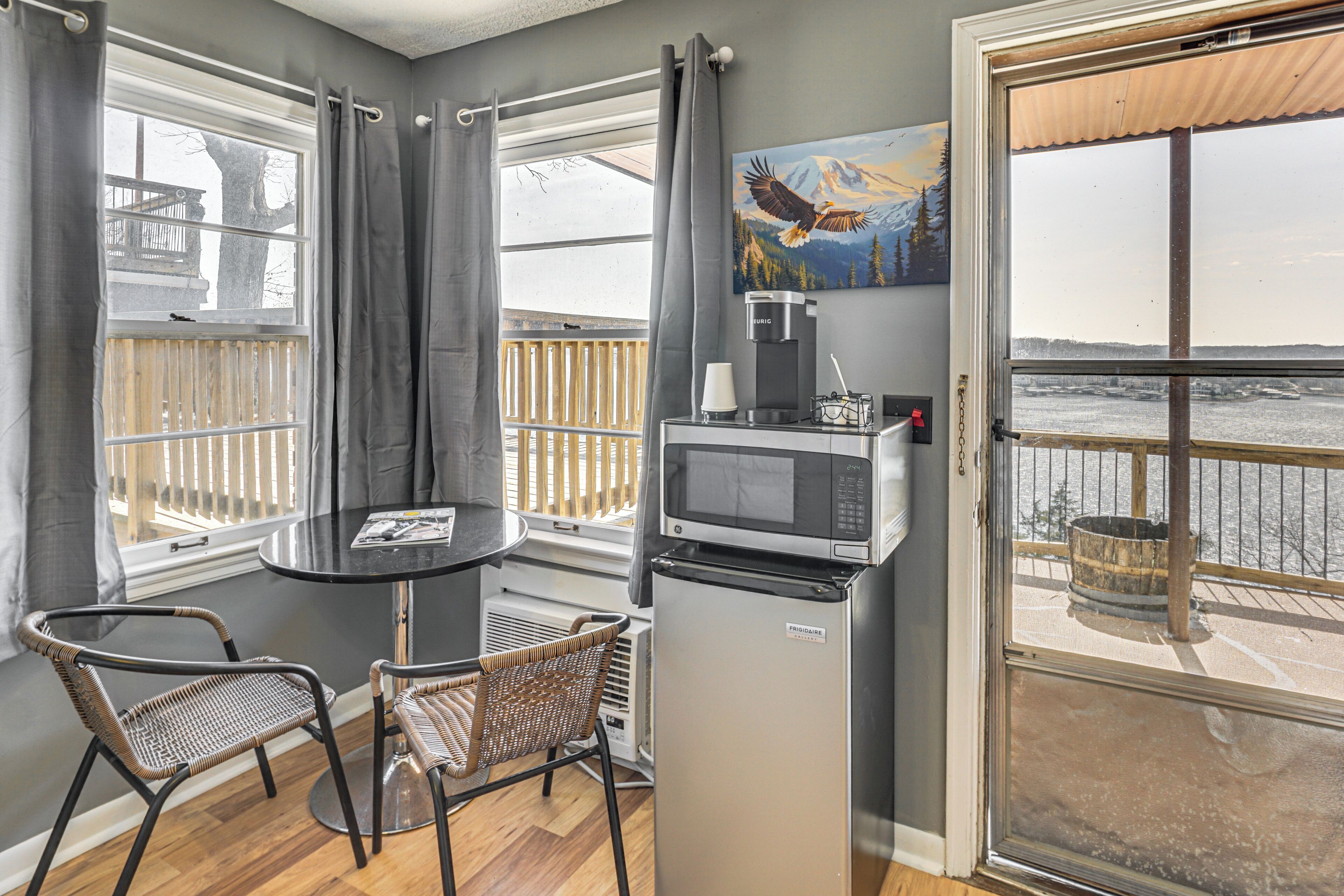 A compact kitchen with a microwave, refrigerator, and dining area with chairs.