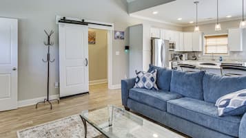 A modern kitchen with white cabinets, a stainless steel refrigerator, and pendant lighting.