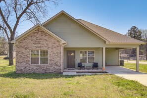 A single-story house with a brick facade, a front porch with two chairs, and a garage door.