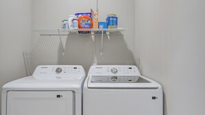 Deux machines à laver à chargement frontal, avec une étagère au-dessus pour y ranger les produits de lessive.