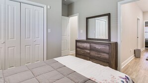 Une chambre à coucher avec un lit, une commode, un miroir et un placard.