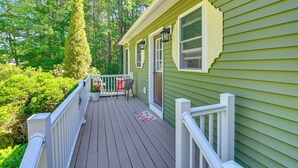 Uma casa verde com deck de madeira, uma porta e uma janela.