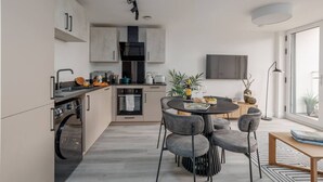 Une cuisine moderne avec un coin repas, un four encastré et un téléviseur fixé au-dessus du plan de travail.