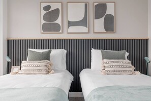 Una cama doble con cabecera a rayas, dos mesitas de noche y una obra de arte abstracto en la pared.