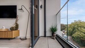 Un salon moderne avec un téléviseur, un meuble en bois, une lampe sur pied et une plante en pot.
