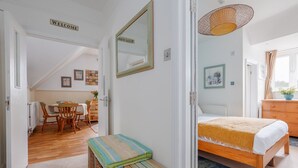 Ein Zimmer mit einem Bett, einem kleinen Tisch, einem Stuhl, einem Korbwäscher und einem Schild mit der Aufschrift 'WELCOME'.