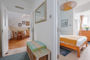 Ein Zimmer mit einem Bett, einem kleinen Tisch, einem Stuhl, einem Korbwäscher und einem Schild mit der Aufschrift 'WELCOME'.