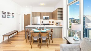 Una cocina moderna con una isla central, sillas de madera y una mesa de comedor preparada para cuatro personas.